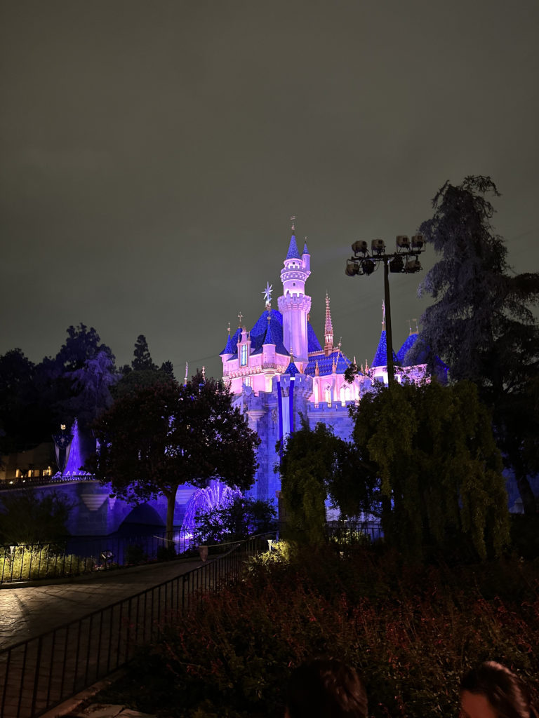 Sleeping Beauty Castle at Disneyland illuminated by lights at night before the firework show