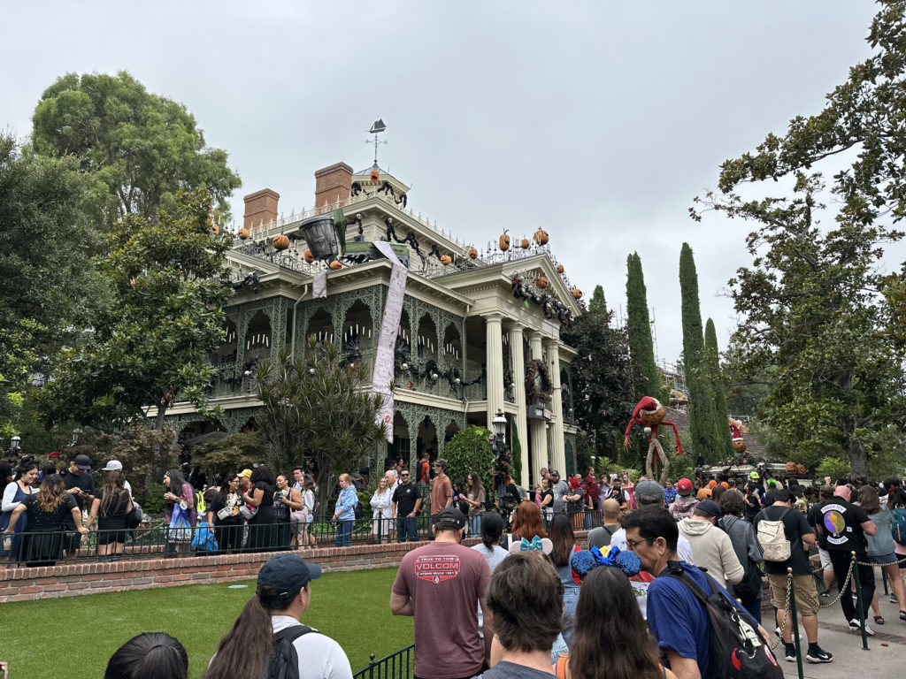 The Haunted Mansion in Disneyland is decorated for Halloween while lines of guest wait for their turn to enter